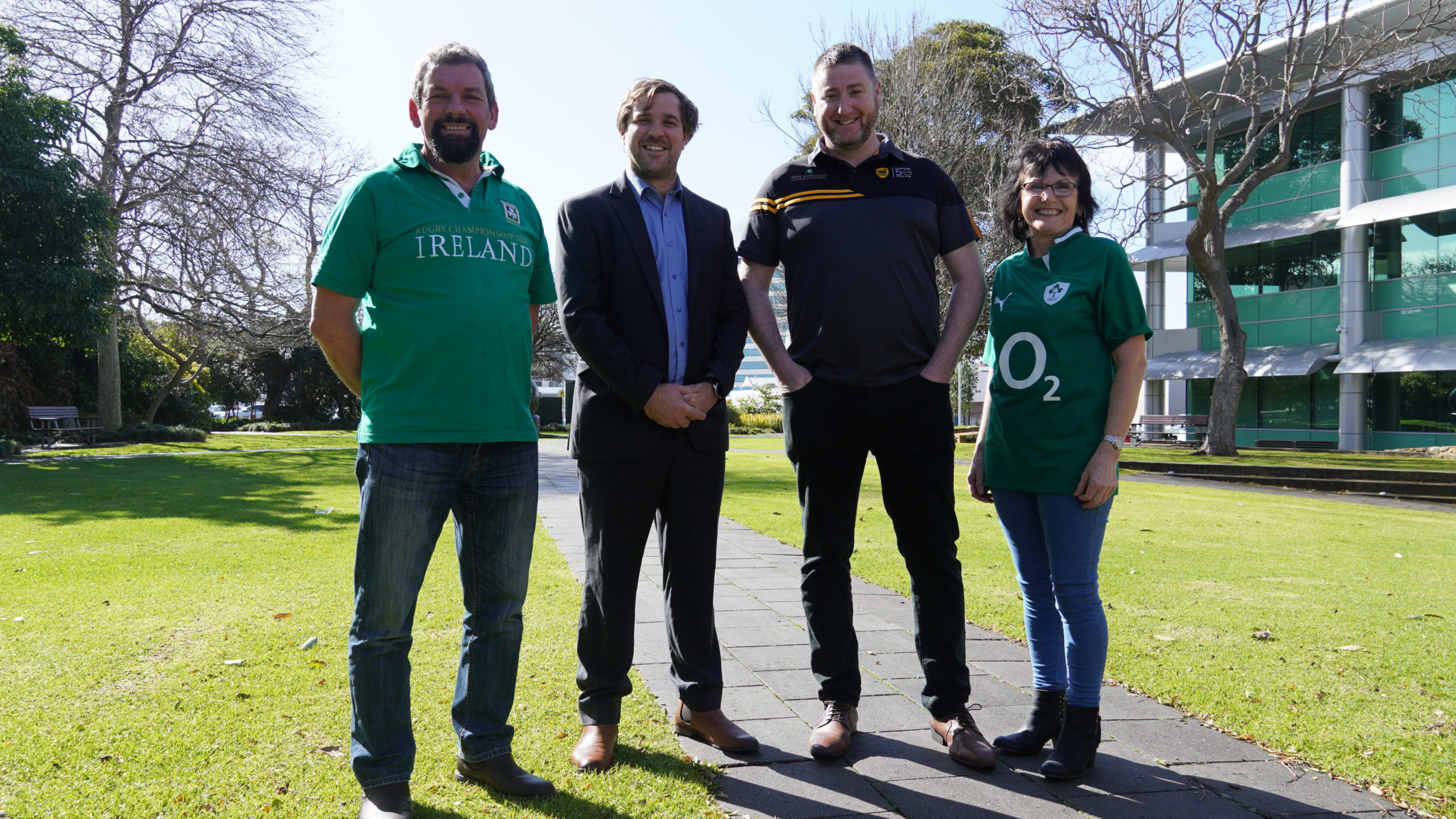 Three men, one wearing a colourful green shirt with the word 'Ireland' on its front, and a woman stand on a pathway in the middle of Bunbury Council Gardens.