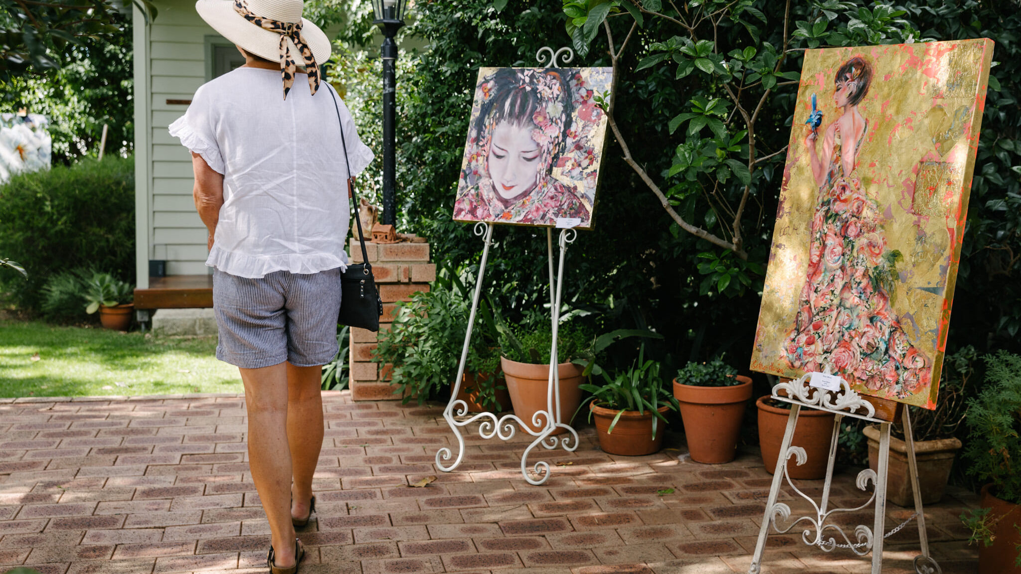 Visitor walking amongst paintings in a garden at the Tree Street Art Safari