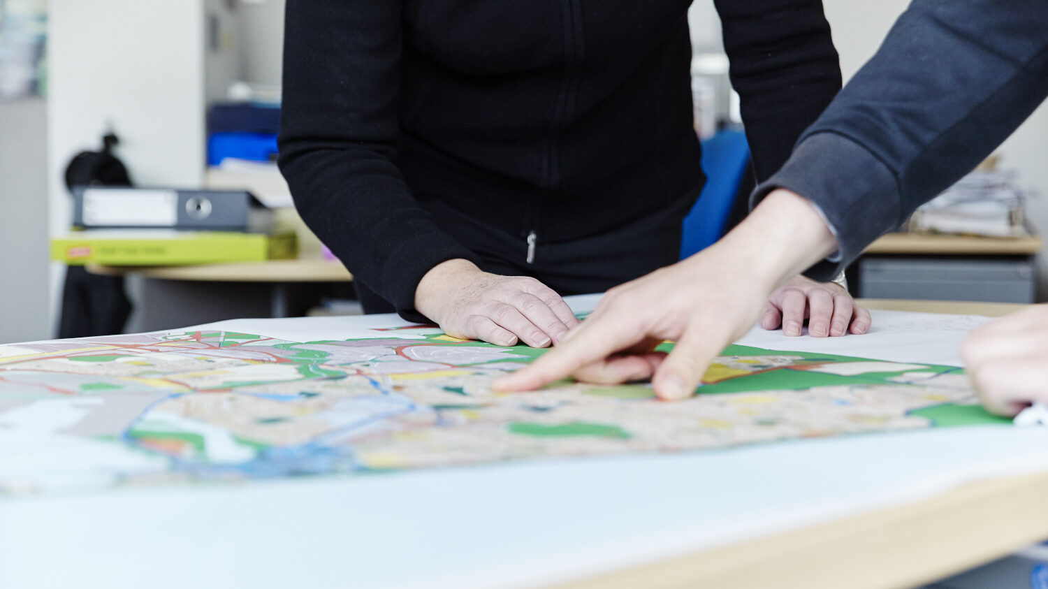 hands pointing on a map resting on a table