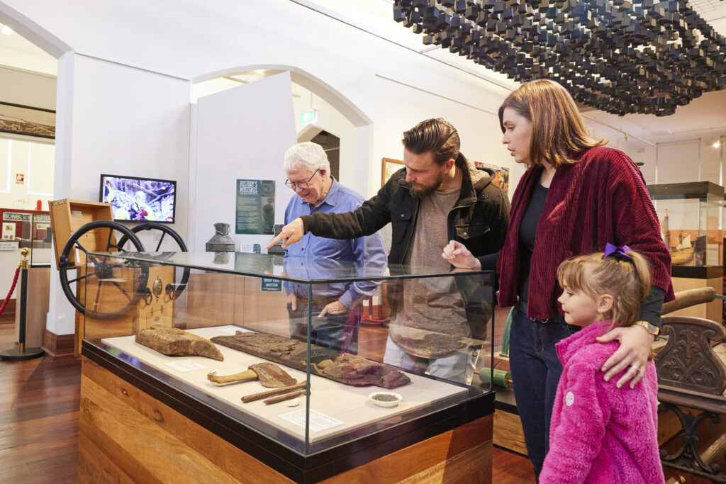 four people viewing items in glass case