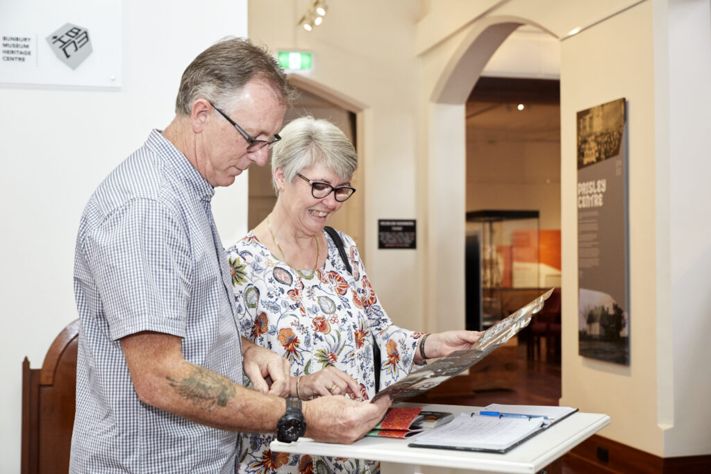 man and woman wearing glasses and looking at brochure inside historic building 