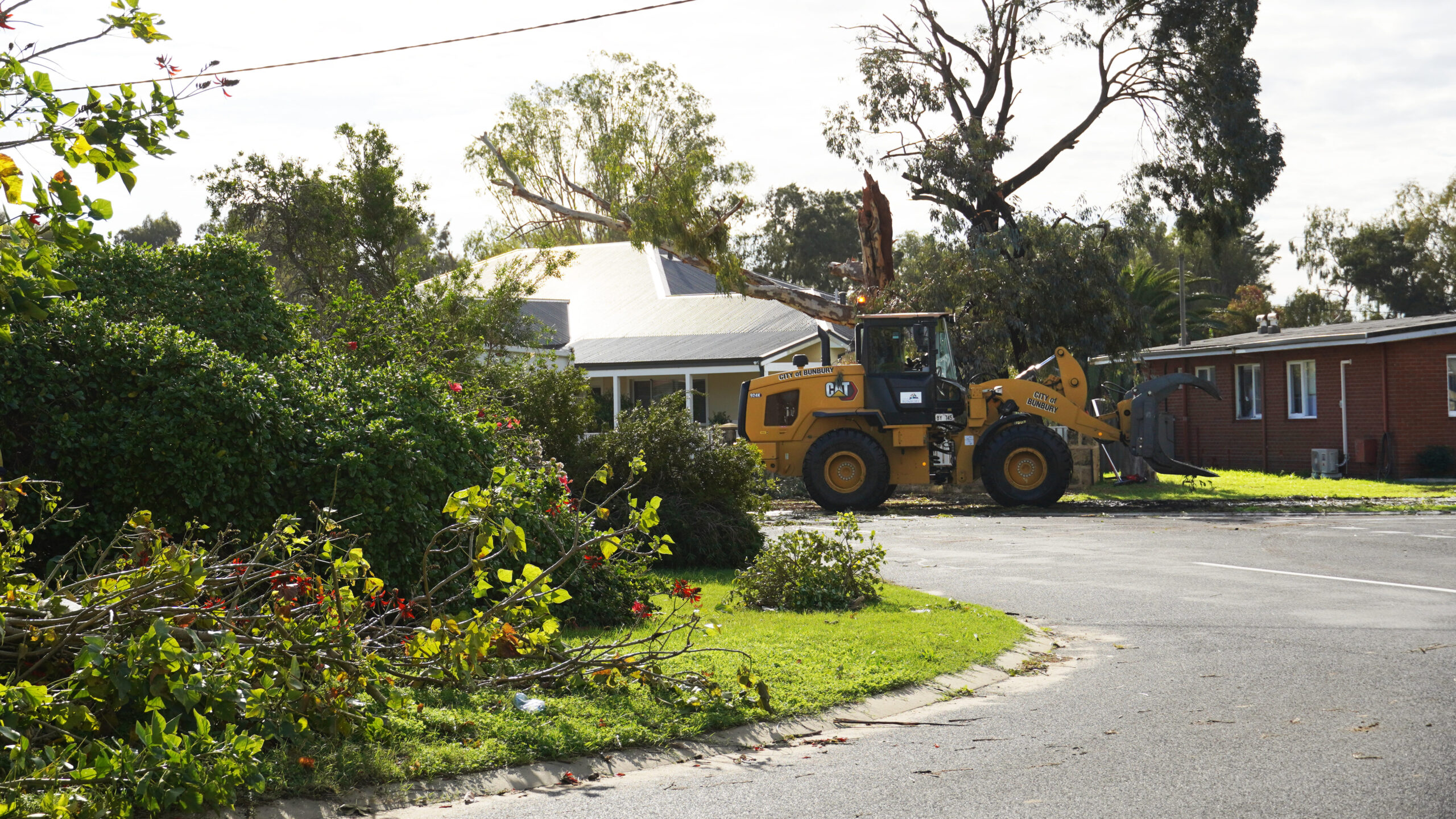 Storm damage in East Bunbury. Fallen trees on a suburban street and a bobcat.