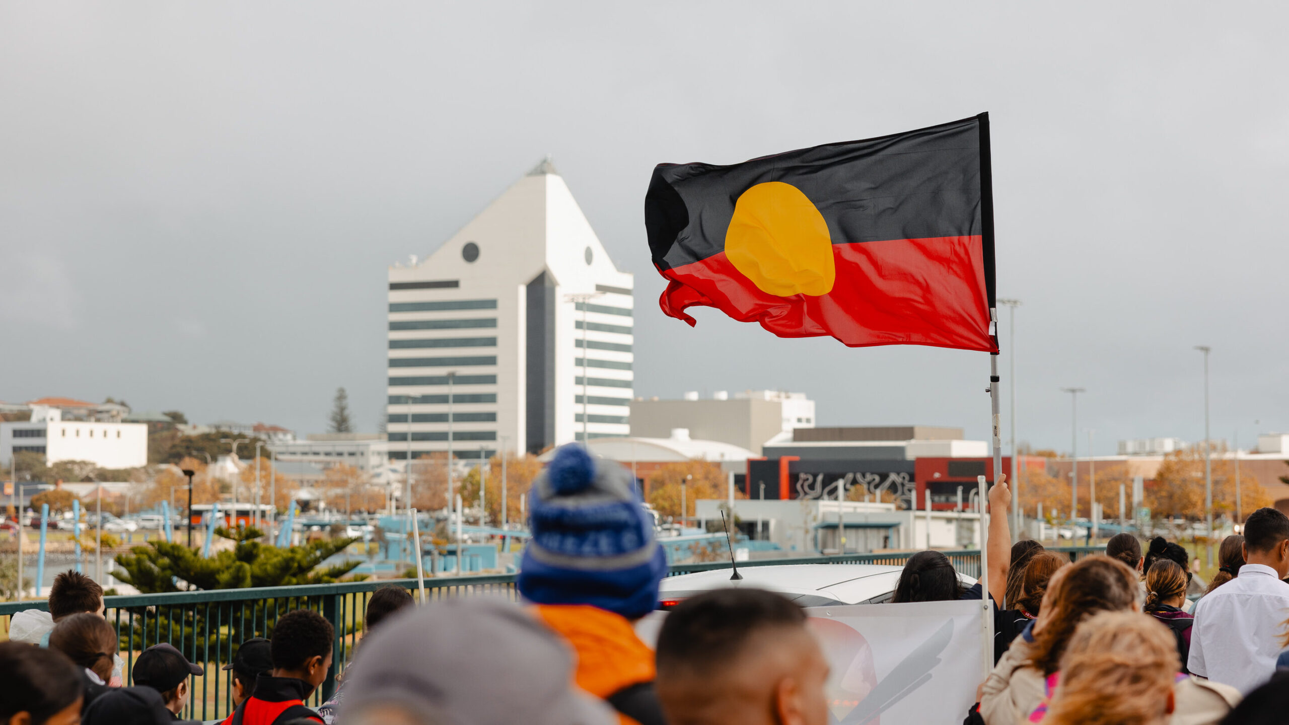 Aboriginal flag above a crowd with the Bunbury tower in the background.